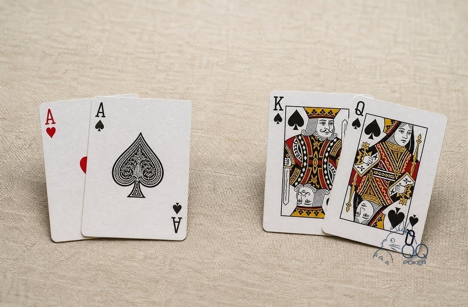 米色亚麻布上左右两组牌：左边一对 A，右边黑桃 K 与黑桃 Q